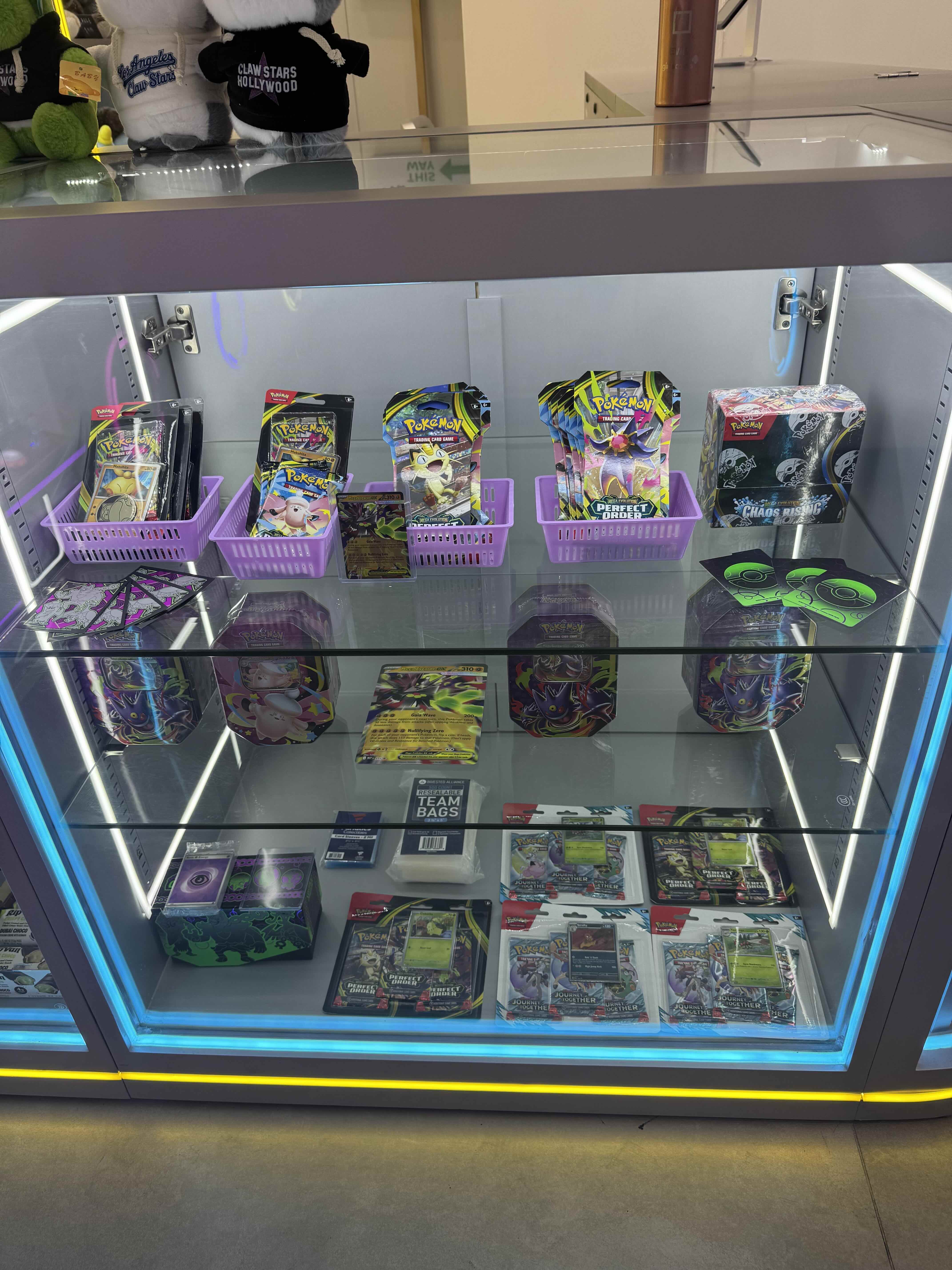 Pokémon trading cards, booster packs, and tins in the Claw Stars display case